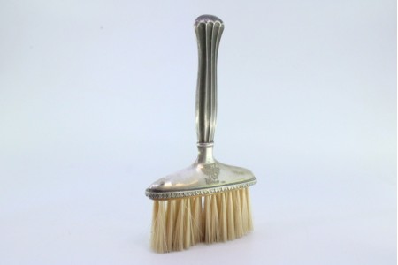 Vassoura em prata com relevos e cabo canelado.